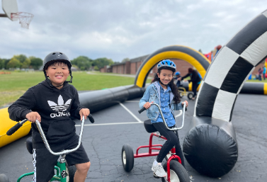 Students riding big tricycles at Family Fun Night!