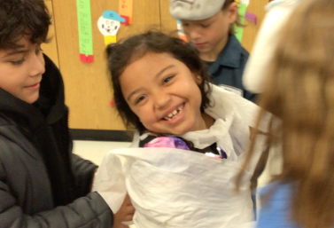 Student being wrapped as a mummy at Halloween party.