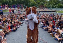 Bulldog Mascot during and outside assembly surrounded by seated students.