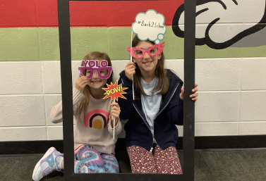 Students posing for a Selfie with glasses and a photo frame.