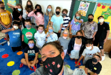 Ms. Meziere posing with Ms. Wessel's class for a selfie on the first day of school. The students are grouped together with Ms. Wessel putting up peace signs and thumbs up behind Ms. Meziere in the forefront near the bottom of the picture. 