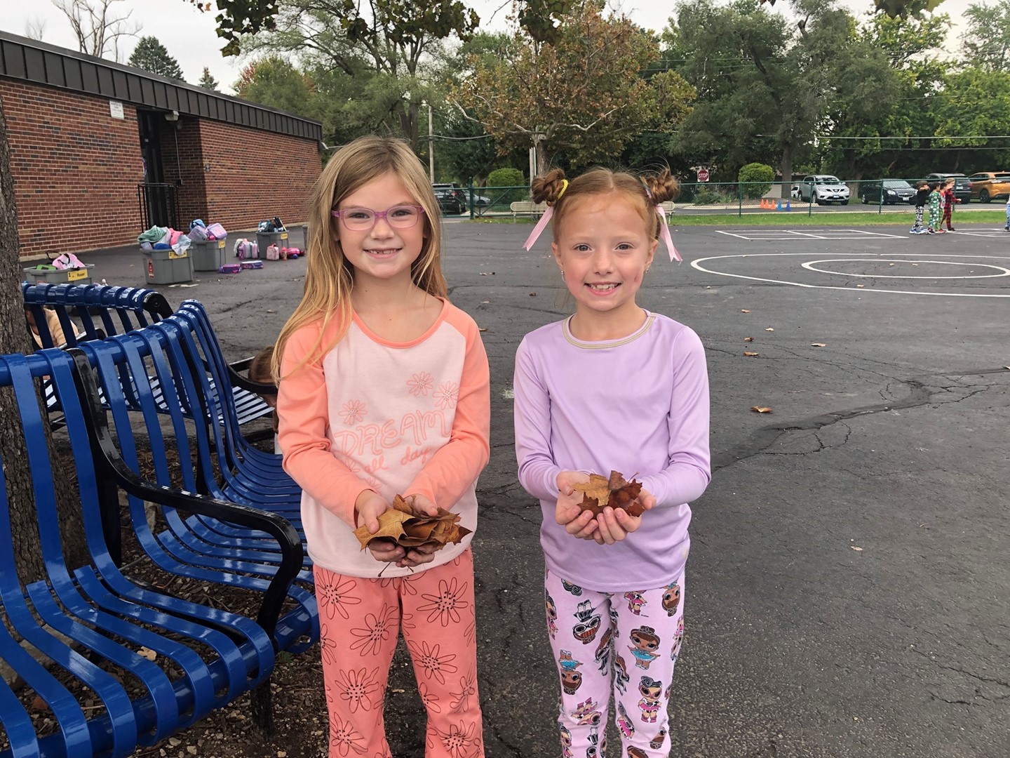 Students holding leaves at recess dressed in pajamas on PJ day.