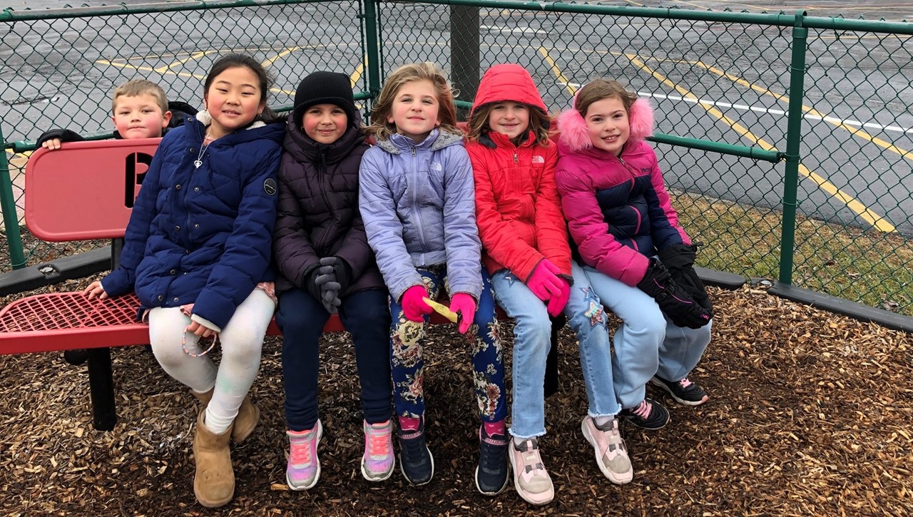 Students at recess sitting on the buddy bench.