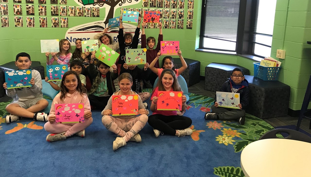 Students won a prize to decorate the the school with spring pictures, so they are showing them off in a picture.