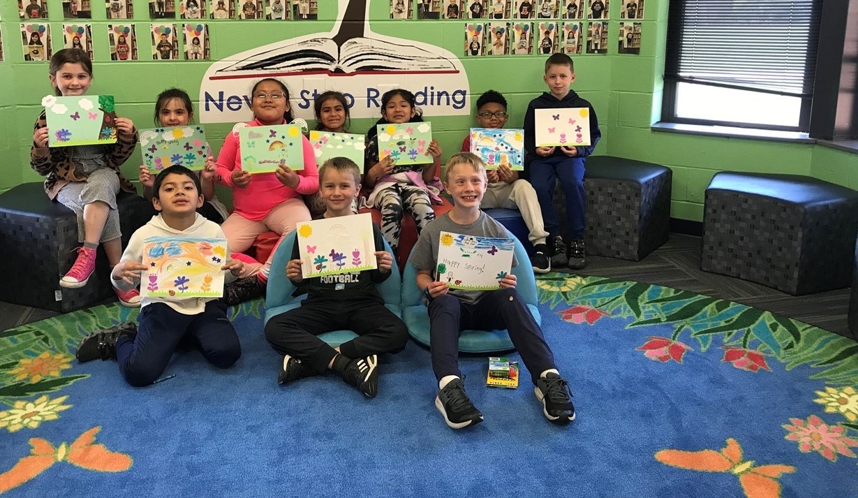Students won a prize to decorate the the school with spring pictures, so they are showing them off in a picture.